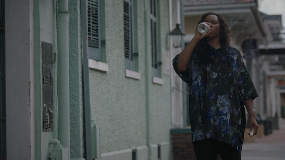 Auntie Chantelle takes a swig of rum while walking down the street with her chalk.