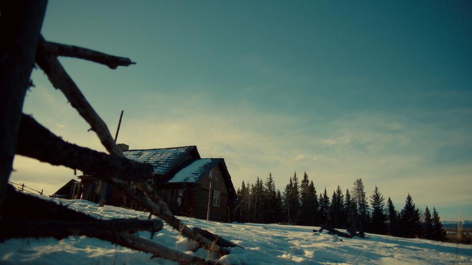 Establishing shot of the cabin in a snowy field.