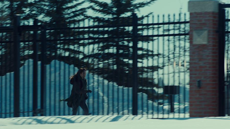 Wynonna runs along the outside fence of the institute to confront her mother.