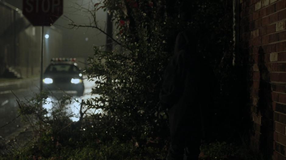 Young Tyrone hides behind some bushes as a police car drives past.