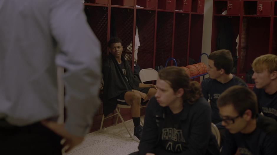 Tyrone looks over as his coach addresses him in the locker room.