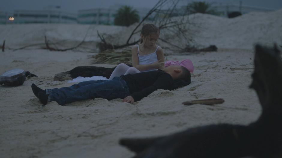 Young Tandy looks down at Tyrone on the beach.