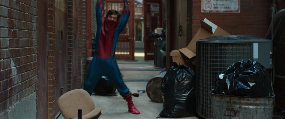 Peter struggles to get his spider suit on in the cluttered alley.