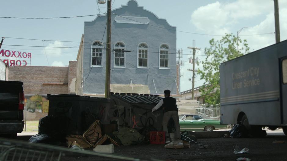 Tyrone looks over at Connors' house and car from behind a dumpster across the street.