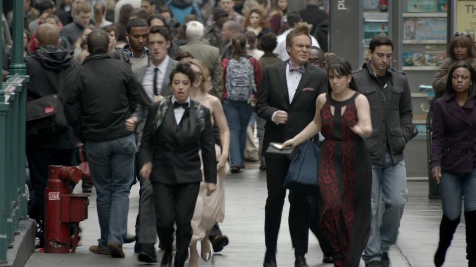 The gang rushes down the busy sidewalk in their fancy wedding chlothes.