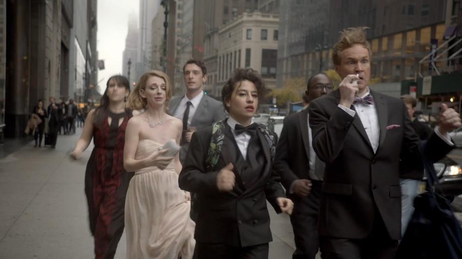 The gang rushes down the sidewalk in their fancy wedding clothes.