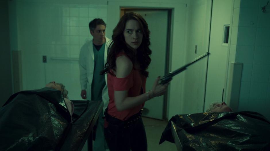 Wynonna holds out her gun while searching the cooler with Dr. Reggie.
