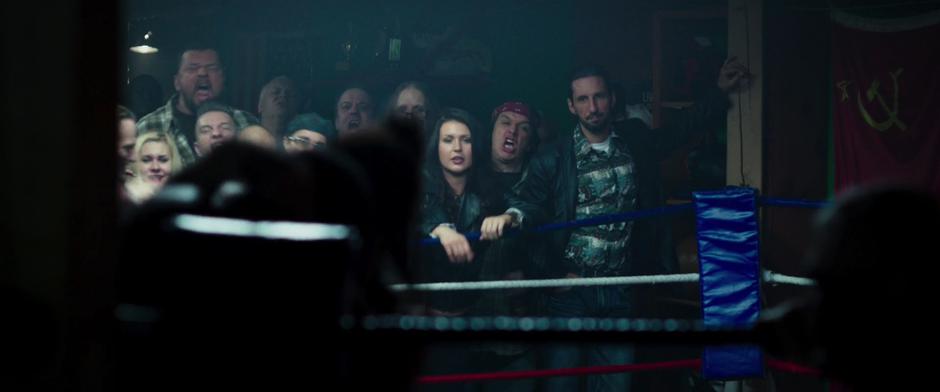 A sleezy man watches the boxing from the crowd.