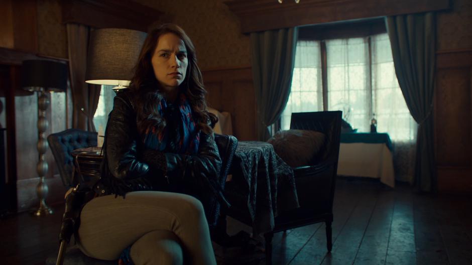 Wynonna sits in the chair and stares over at Kate with attitude.
