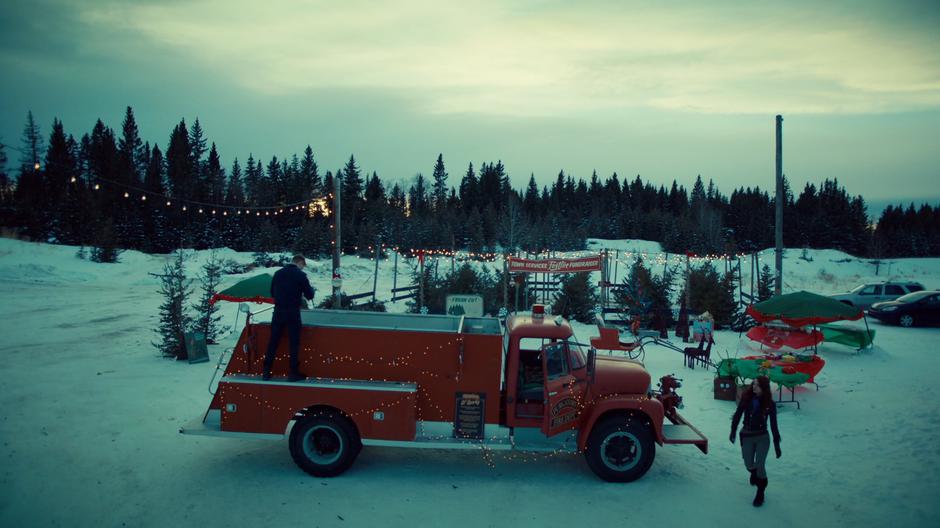 Wynonna walks around the side of the vintage fire truck to where Charlie is packing up Christmas lights.