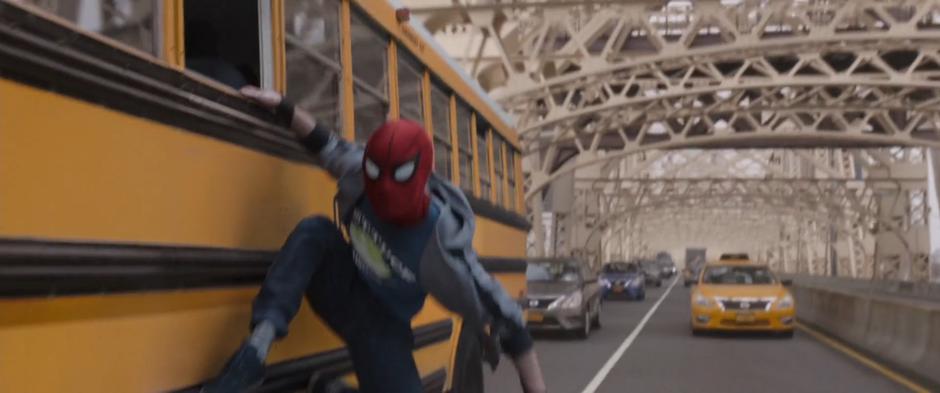 Peter leans off he side of the school bus wearing his Spider-Man mask and street clothes.