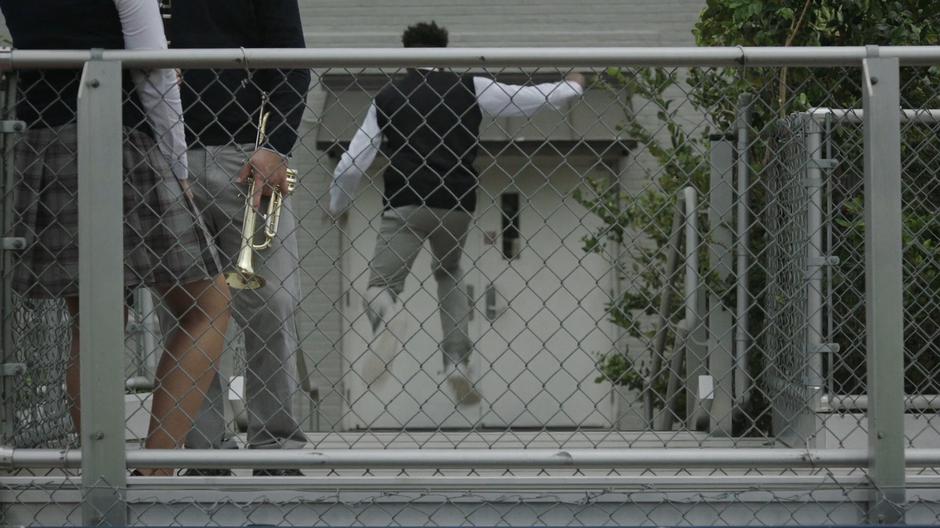 Tyrone jumps down the bleecher stairs to the gym doors.