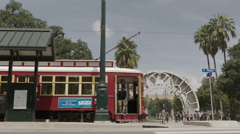 Tyrone steps out of the streetcar across from the park.