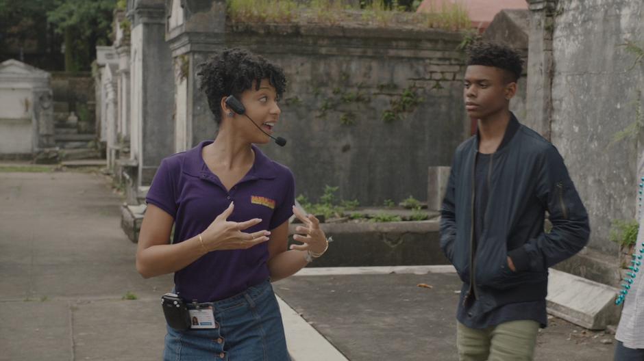 Evita turns around to talk with the tour group while Tyrone follows her.