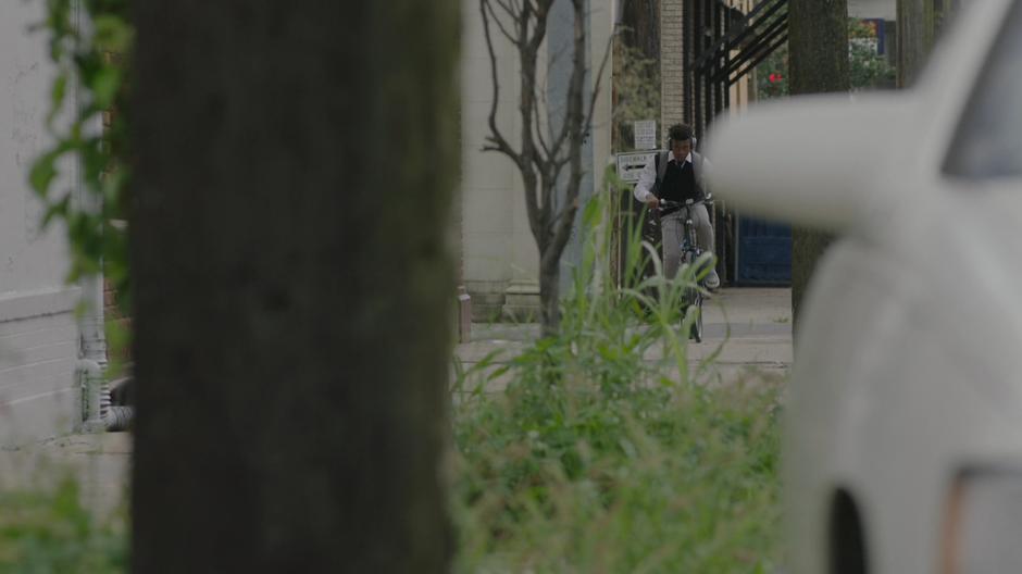 Tyrone rides down the sidewalk while listening to his headphones.