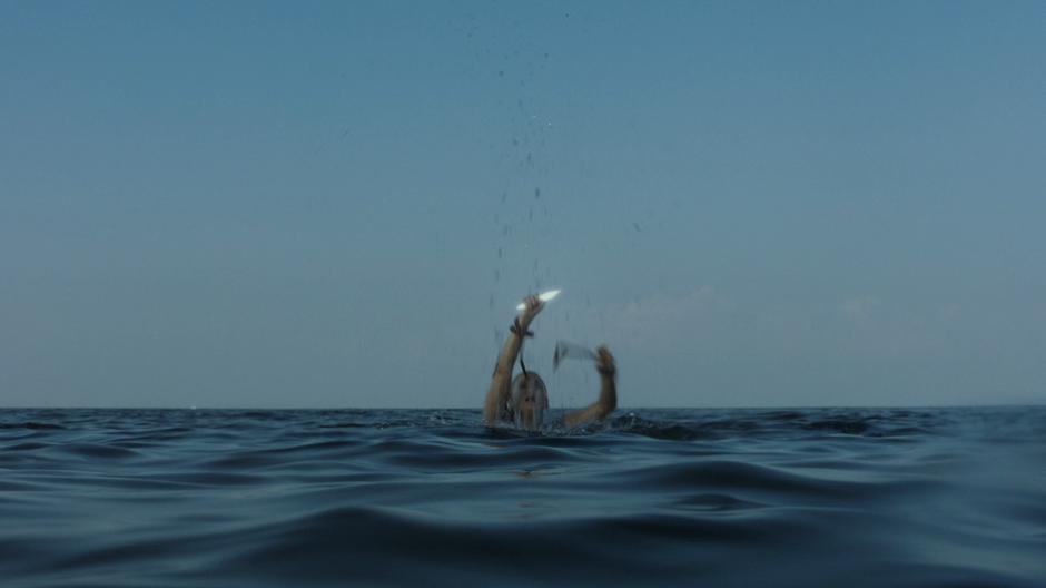 Tandy cuts the rope with one of her light daggers in the water.