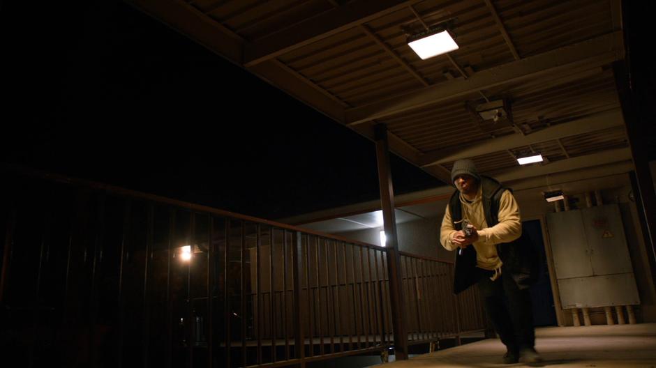 A gang member runs along the walkway with his gun drawn.