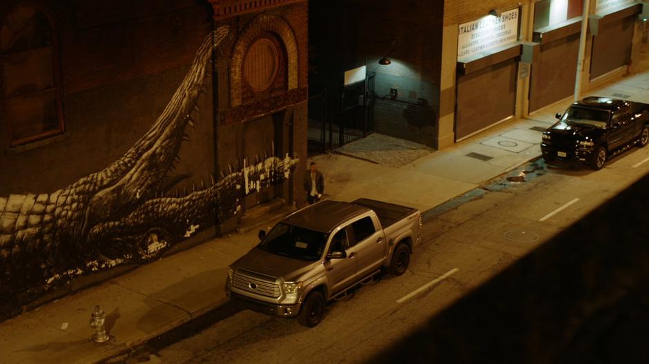 The gang member walks out of an alley in front of the march.