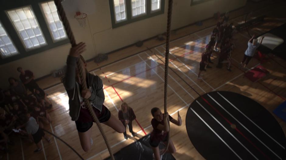 Kara climbs up the rope in the gym very quickly.