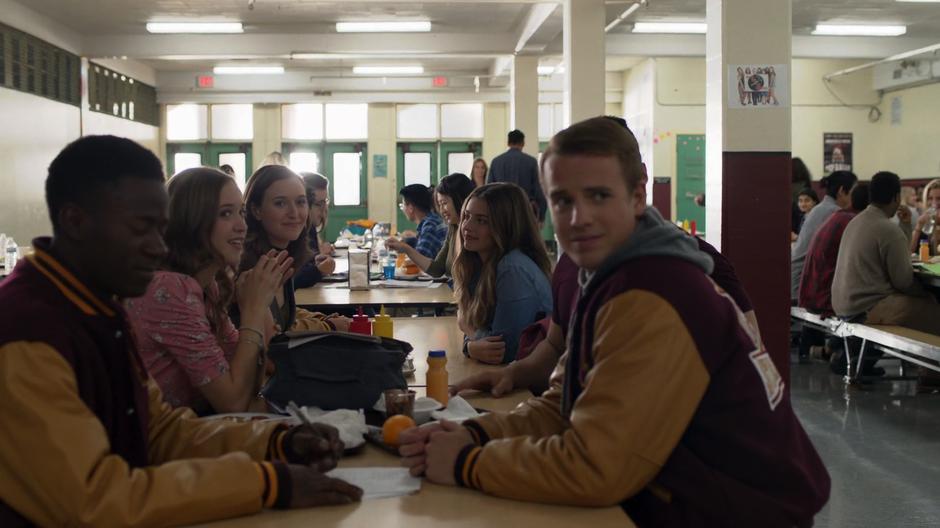 Alex and her popular friends look over at Kenny Li from their table.