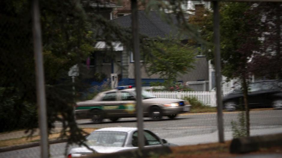 A police car drives down the street next to the school.