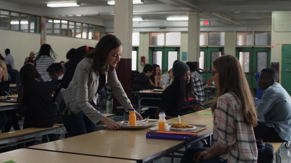 Alex sits down at the table with Kara.