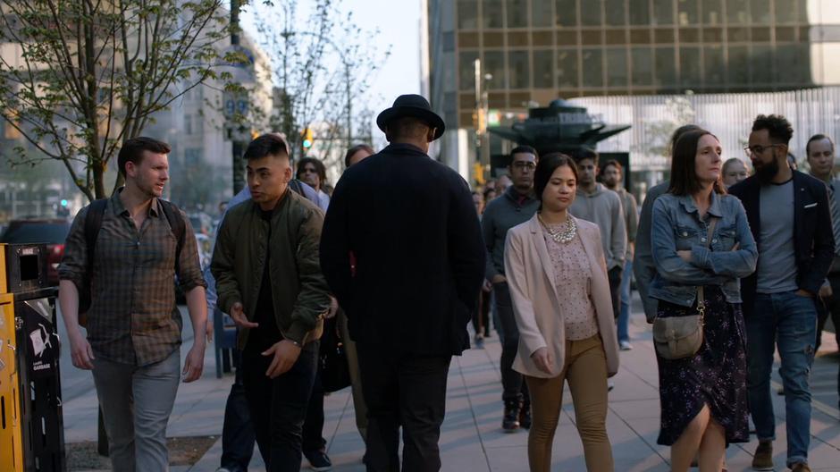 J'onn walks off through the crowd in his nice hat.