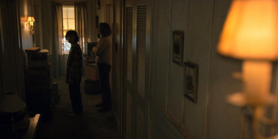 Eleven sees a flashing light on the wall while walking in the hallway with Becky Ives.