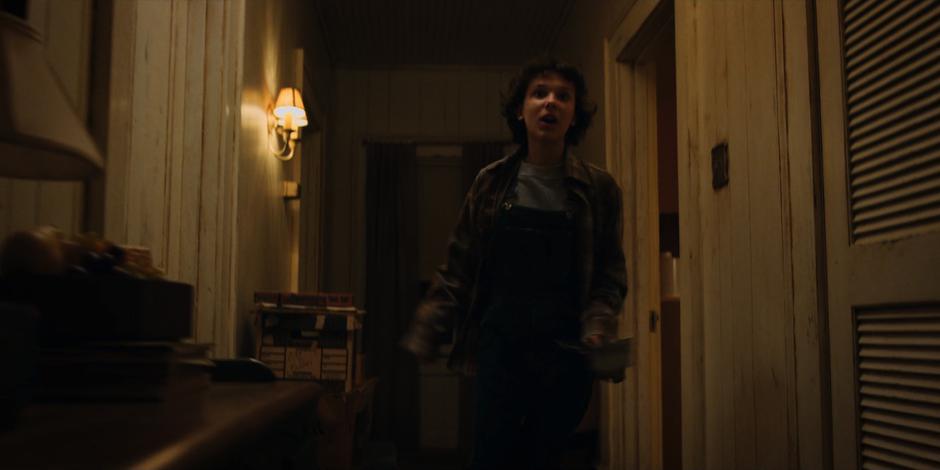 Eleven runs down the hallway towards the front door.