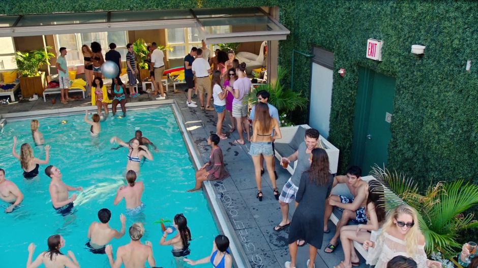 People party in and around the pool on the rooftop.