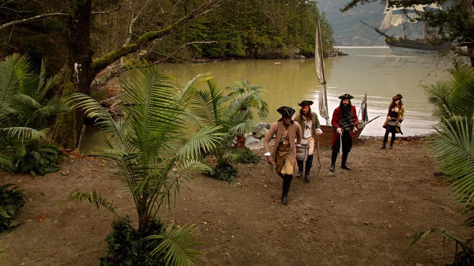 Blackbeard watches as two of his men carry the treasure chest away from the boat as Anne walks up to him.