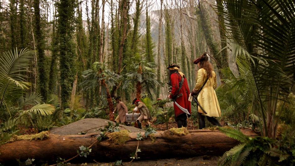 Blackbeard and Anne watch as the two other pirates carry the treasure into the woods.