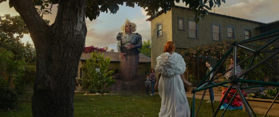 A giant Mrs. Which stands over the yard while the others look over as Mrs. Whatsit talks.