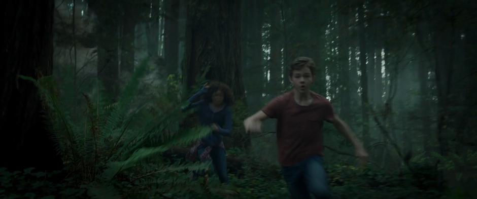 Meg and Calvin run through the woods as it collapses behind them.