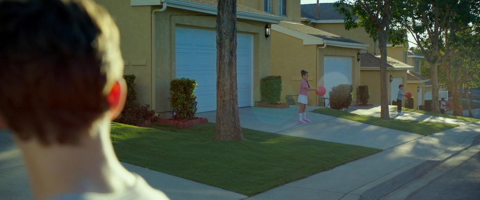 Calvin looks down the street and sees several children bouncing balls in unison.