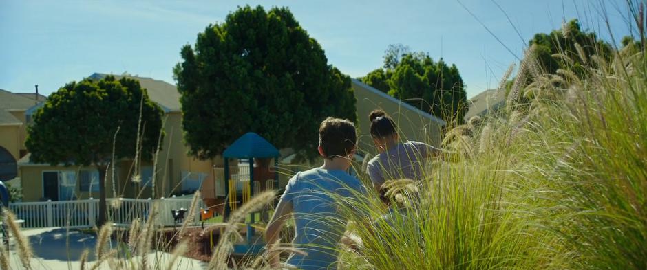 Calvin, Charles Wallace, and Meg climb out of the tall grass and down into the neighborhood.