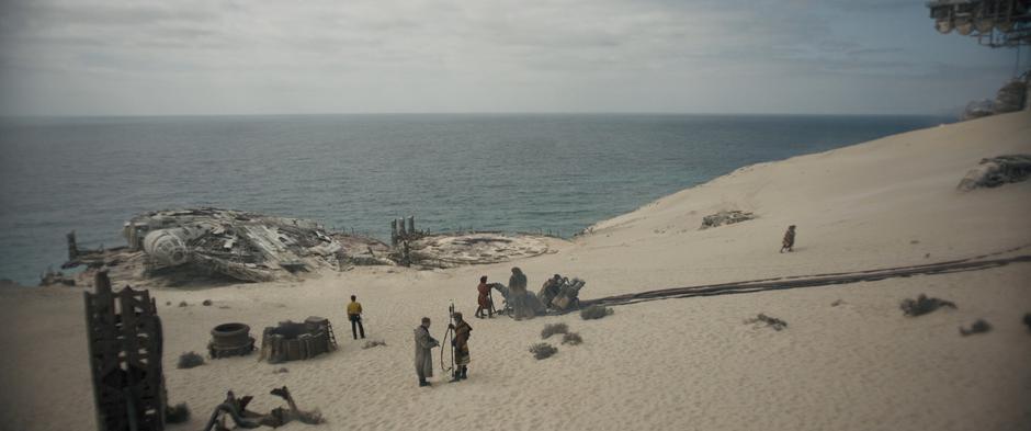 Lando stares down at his trashed ship while Beckett talks to some locals and Han and Chewie hook up some wires to refuel the Falcon which lies askew on the landing platform.