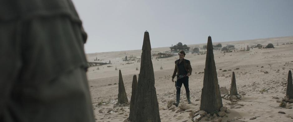 Han walks down across the sand to where Beckett is sulking.