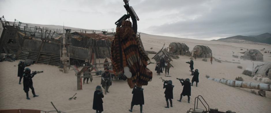 Enfys Nest leaps down from above to attack the soliders who have surrounded her Cloud Riders.