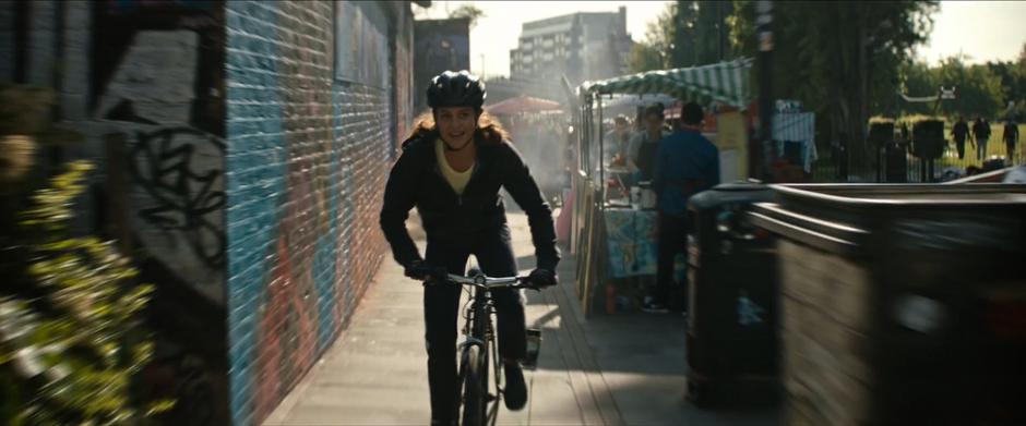 Lara rides down the alley past several food stands.