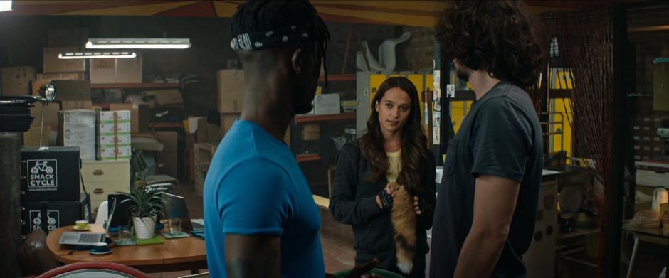 Lara holds the fox's tail while talking to her two coworkers.