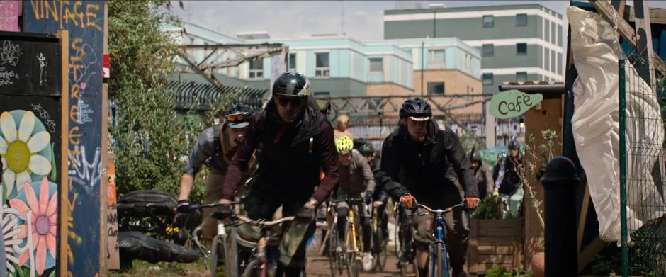 The bicyclists chasing Lara set off out of the garden.