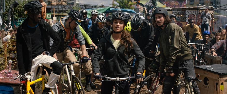 Lara stands on her bike at the front of the crowd and prepares to race.