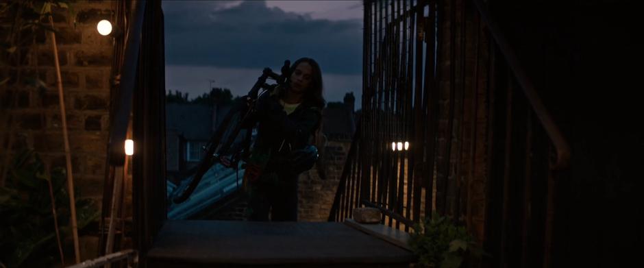 Lara carries her bike up to the roof of the building.