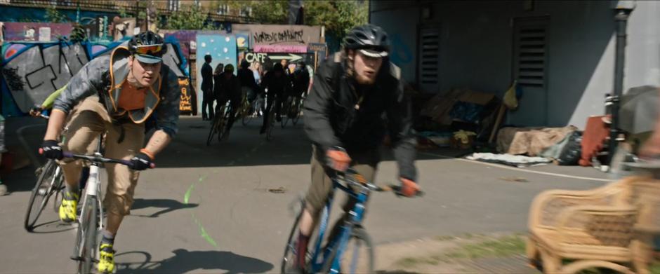 Bicyclists follow the paint line under a bridge.