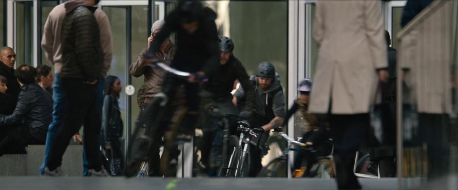 The swarm of bicyclists ride through the browd of business people.