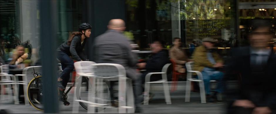 Lara rides through the outdoor seating of a restaurant.