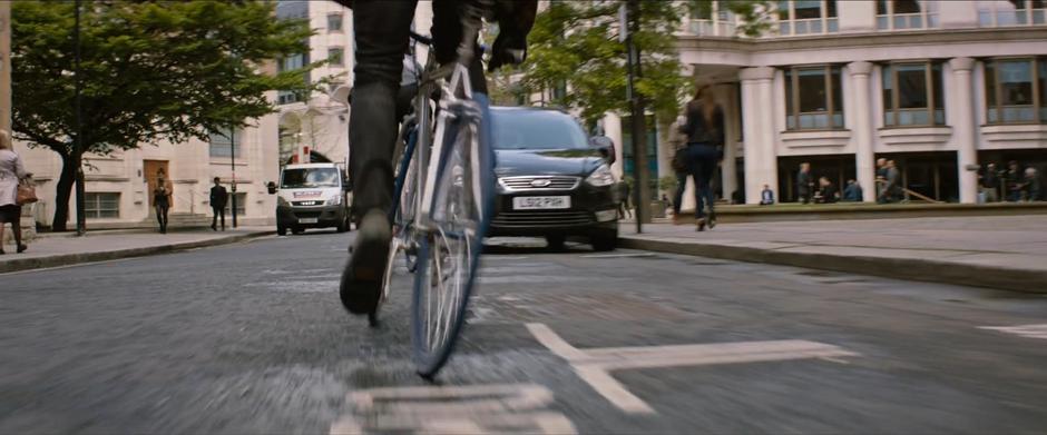 One of the bicyclists rides down the street looking for Lara.