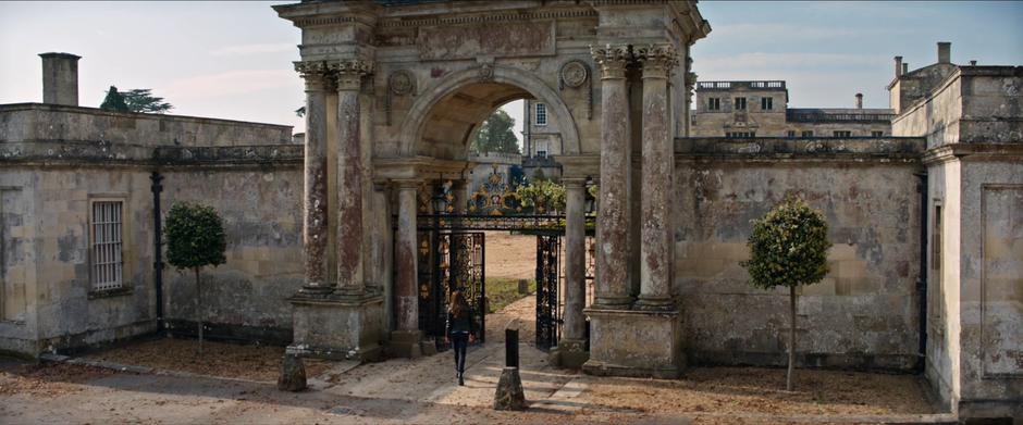 Lara walks in through the gates into her estate grounds.