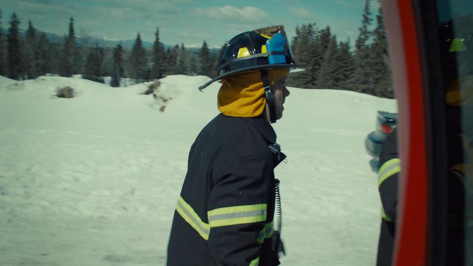 A fire fighter exits the truck and heads towards the burning cabin.